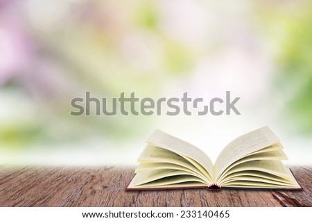 Open book on the wooden table, over abstract light background.