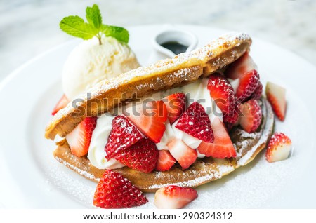 Waffles with strawberries with ice cream. Extra honey on white plate.
