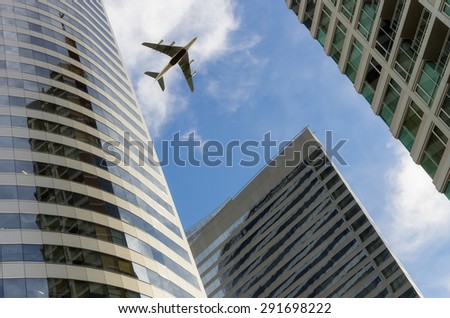 Airplane flying above glass office buildings. Wide lens effect.