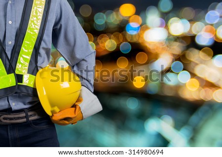Engineers holding a yellow helmet for the safety of workers. With background blurred light.
