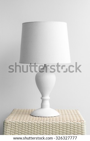 Lamp on a night table next to a bed.