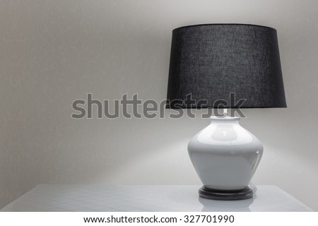 Lamp on a night table next to a bed.