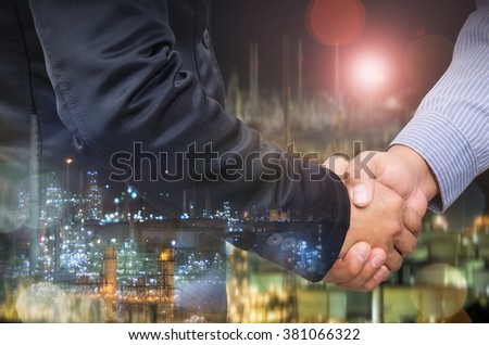 Double exposure of businessman handshake and industrial background.