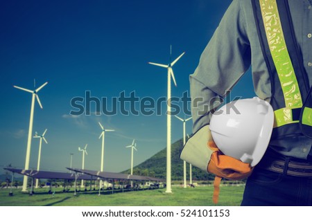 Engineer holding a whwite helmet. Against a backdrop of renewable energy farms. Vintage Style.