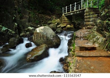 Mysterious bridge and small beautiful waterfall in tropical forest.