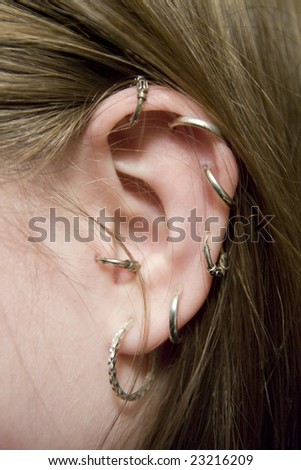 color closeup picture of  lady ear with multiple earrings
