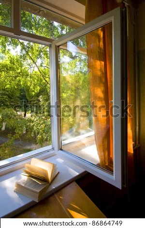 Opened plastic window  with book open and view to green trees