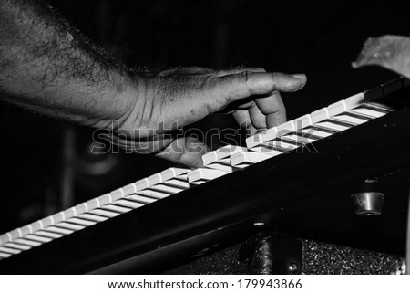 Black and white keyboard music keys and hand fingers pressing the keys