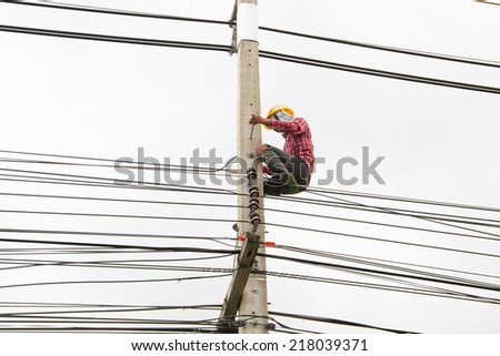 Electrician worker at climbing work on electric post power pole