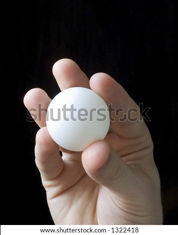 Hand holding lottery ball. Isolated on black.  Blank and unnumbered winner lottery ball