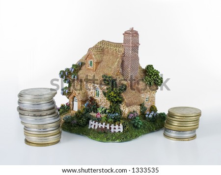 Small house figure with money coins, isolated on white. Good concept for bank credit for buying house. Home sweet home.