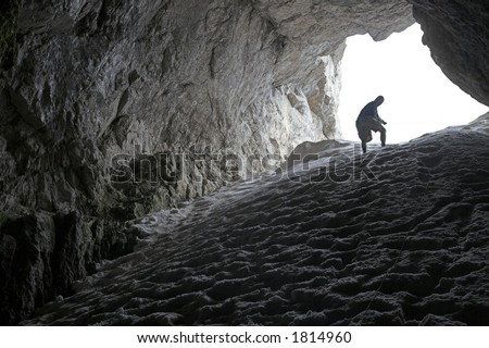 Man descending into the dark cave. Snow cave