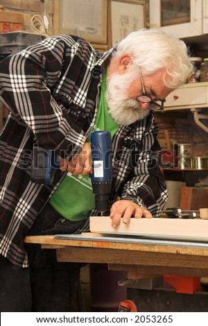 Old man working. Old man with grey beard making something