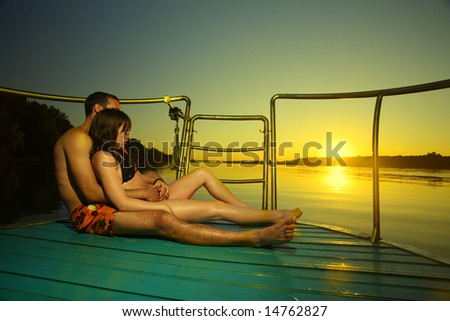 Couple in hug on boat enjoying summer sunset vacation in love. Clear sky and vivid yellow colors. Holiday concept