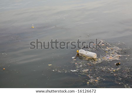 Water pollution and environment conservation concept - plastic bottle on river surface