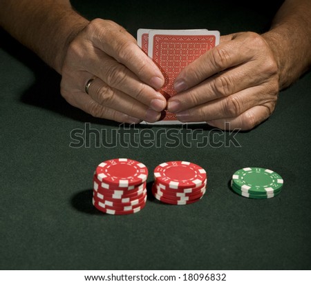 Casino chips on a green background and poker player in Vegas holding cards