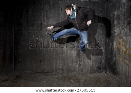 Man jumping in old black grungy room corner with shadows - breakdance concept