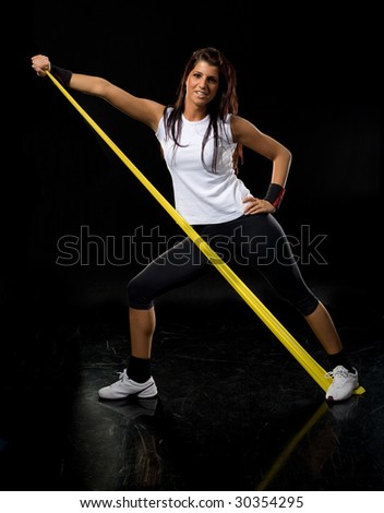 Young fitness  woman exercising in gym with rubber band  isolated on black