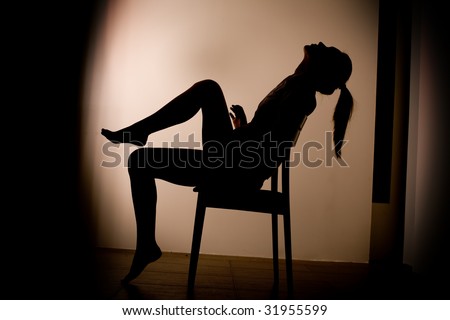 Back light, studio shot of a young, beautiful, sexy woman on chair - silhouette