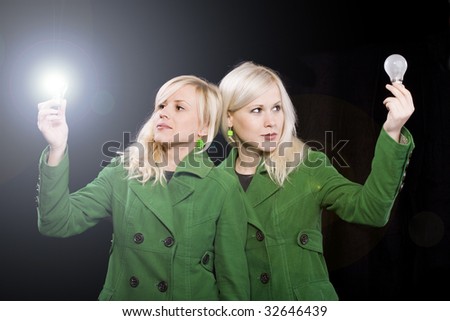 Young women holding working light bulb and other is off. Beautiful sister with idea concept