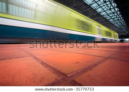 Commuter train in motion blur enters the city station