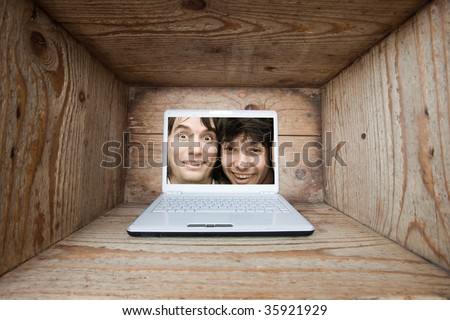 Two young man trapped inside laptop computer in old wooden box interior