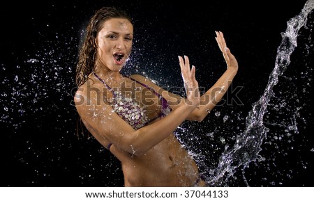 Young woman in bikini with water splashing on her