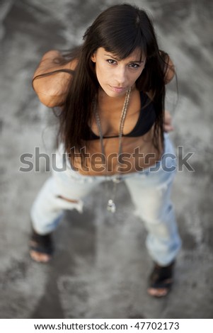 Young sexy woman starring at the camera in bikini top and jeans. Shallow DOF, focus on eyes