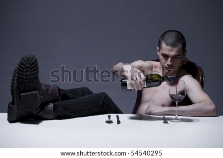 Young man pouring wine in broken glass with boots on dinner table