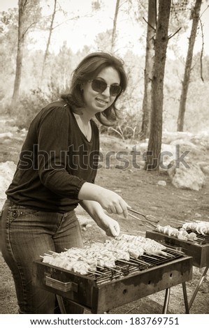 woman cooking meat on portable barbecue and smile
