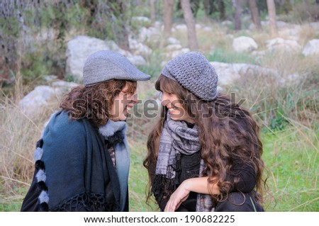 Happy female friends with hats and scarfs in a forest, laughing