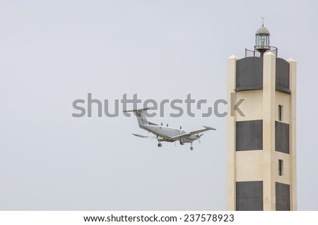 A lighthouse and Small private jet landing or taking off with background of grey sky