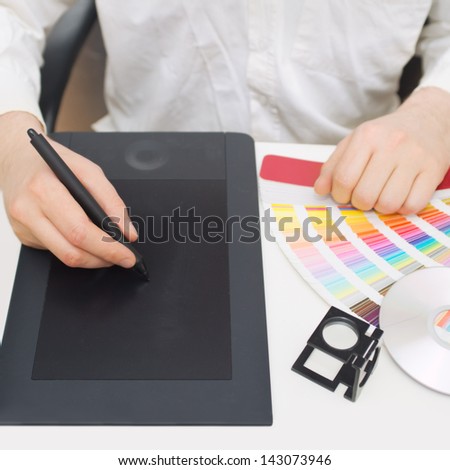 Graphic design, printing, advertising Graphic designer working with digitizer, magnifier, pantone palette, dvd
