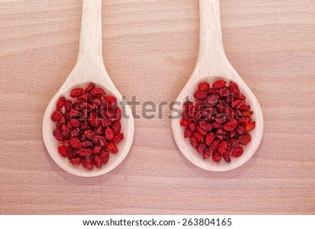 dried barberries in wooden spoon on wooden plate