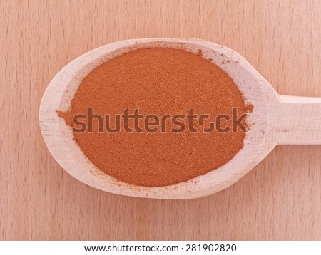 Heap of cat\'s claw plant powder (Uncaria tomentosa) in wooden spoon over wooden plate