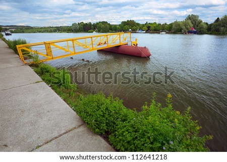 View of a small pier on river Moselle(border river) in city Remich / Luxembourg, evening, summer, in the distance(to right) a campground in Germany