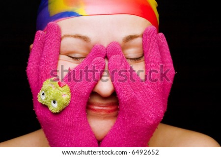 Smiling woman with pink gloves with green frog; black background