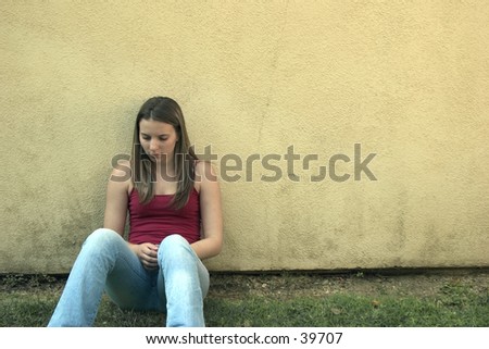 A young woman leaning against a wall.