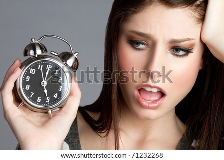 Annoyed woman holding alarm clock