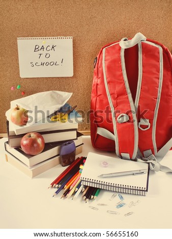 A red school back pack or book bag overflowing with school supplies