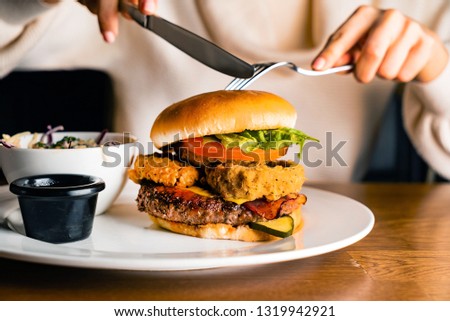 Young woman eating burger in restaurant