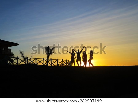 silhouette of friends jumping in sunset at beach