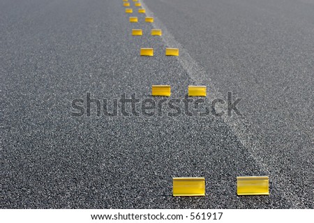 road work - abstract background with temporary yellow markings on fresh pavement. shallow depth of field with focus on first pair of markers.