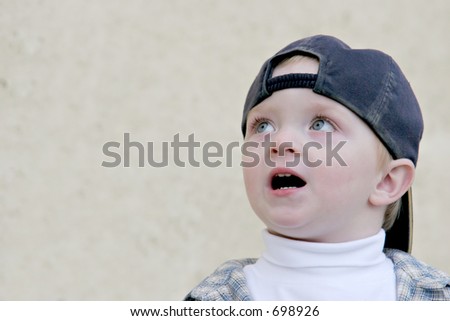 cute young boy wearing a baseball cap, looking up fearful and surprised. plenty of room for copyspace.