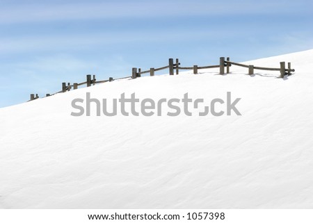 fence on snowy hill with blue sky
