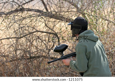 paintball - teen with paintball gun and face mask looking out for the enemy