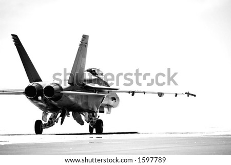 F18 taxiing to runway for takeoff. converted to b&w with overexposed background, focus on rear of aircraft.