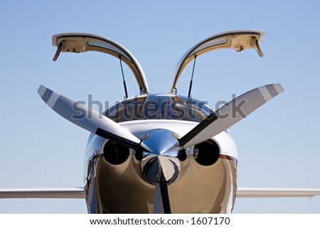 small private aircraft with doors up, against blue sky with limited dof