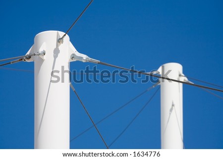 modern architecture - white pillars with steel cables supporting the roofing against blue sky