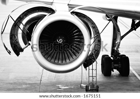 aircraft engine maintenance / servicing - opened panels of a large engine of parked aircraft. highkey b&w image, slight grain.